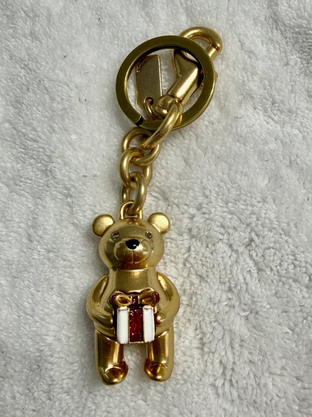 Coach bear charm holding a gift